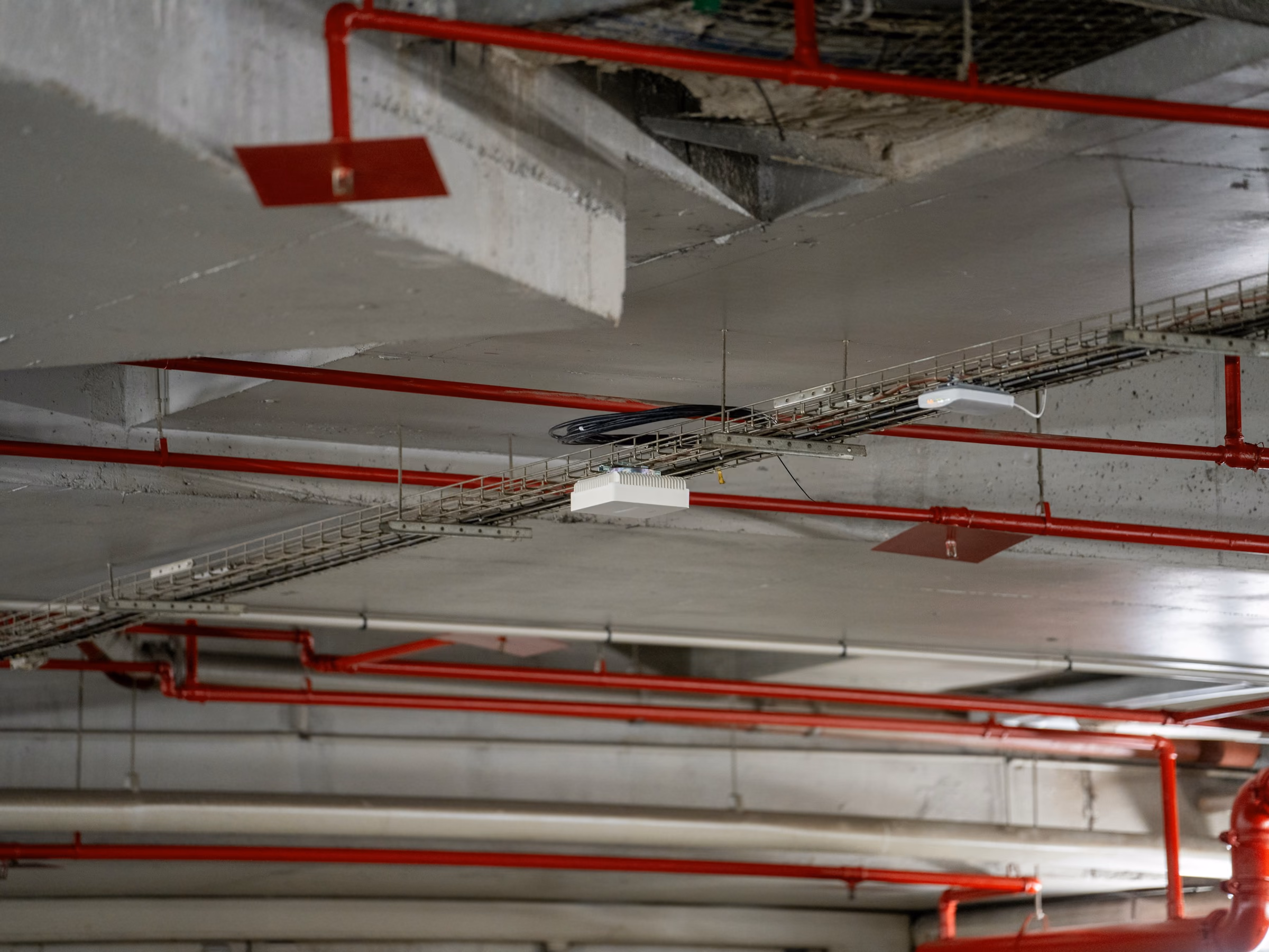 Plafond technique avec canalisations rouges du réseau incendie et chemins de câbles