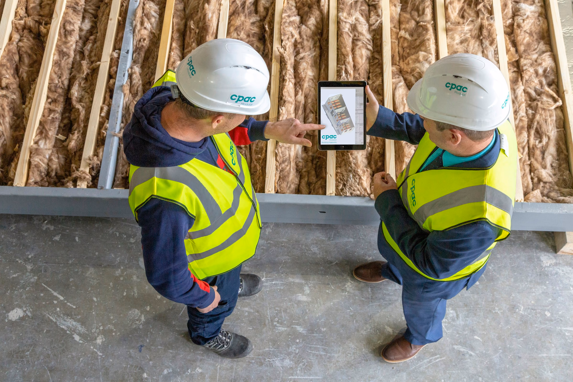 Deux techniciens en casque consultent un plan sur une tablette