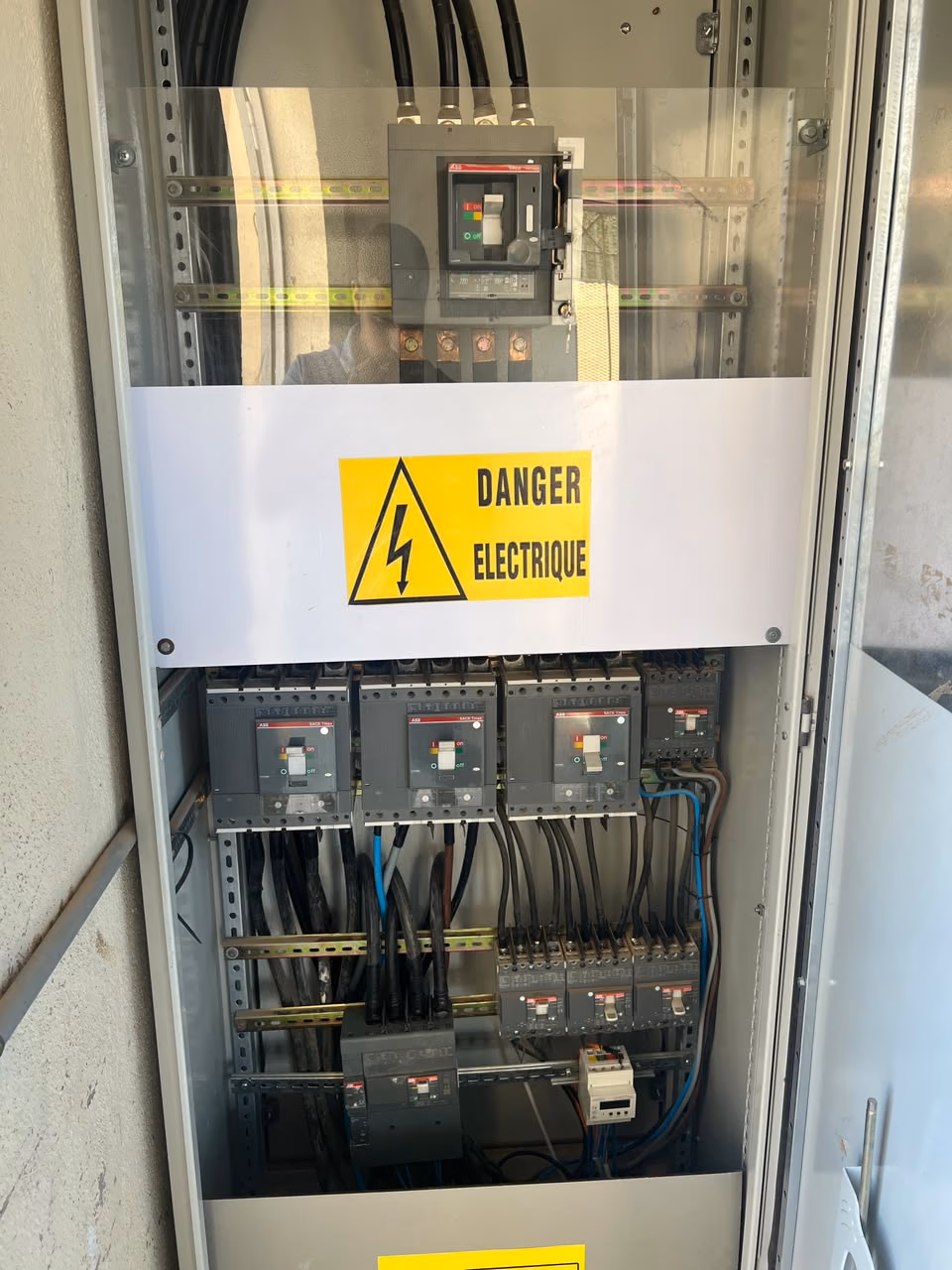 Armoire électrique ouverte avec panneau Danger électrique et disjoncteurs